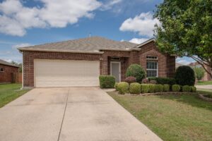 Front exterior of a single-story brick and stone home at 1300 Shelby Ct, Wylie, Texas, featuring a manicured lawn, young tree, and welcoming entrance with a covered porch.