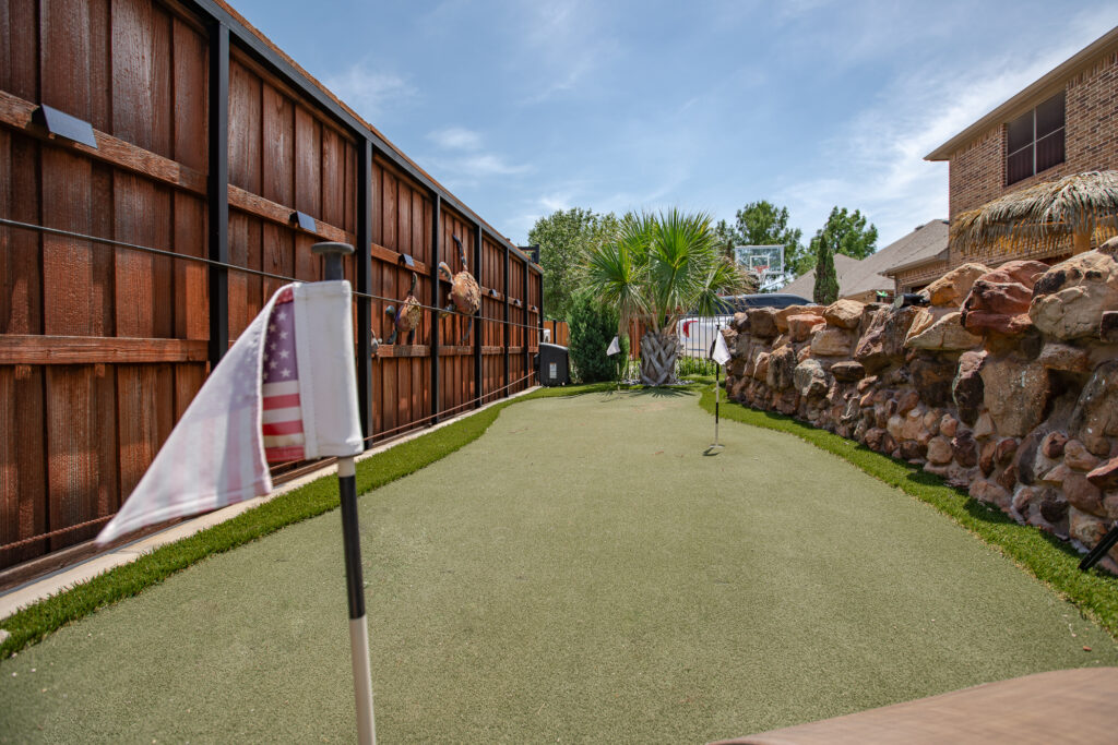 Putting green along privacy fence with decorative fencing and palm plants