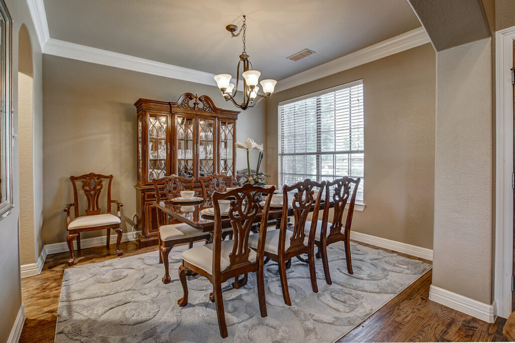 Formal dining room with large window, chandelier, and elegant furniture