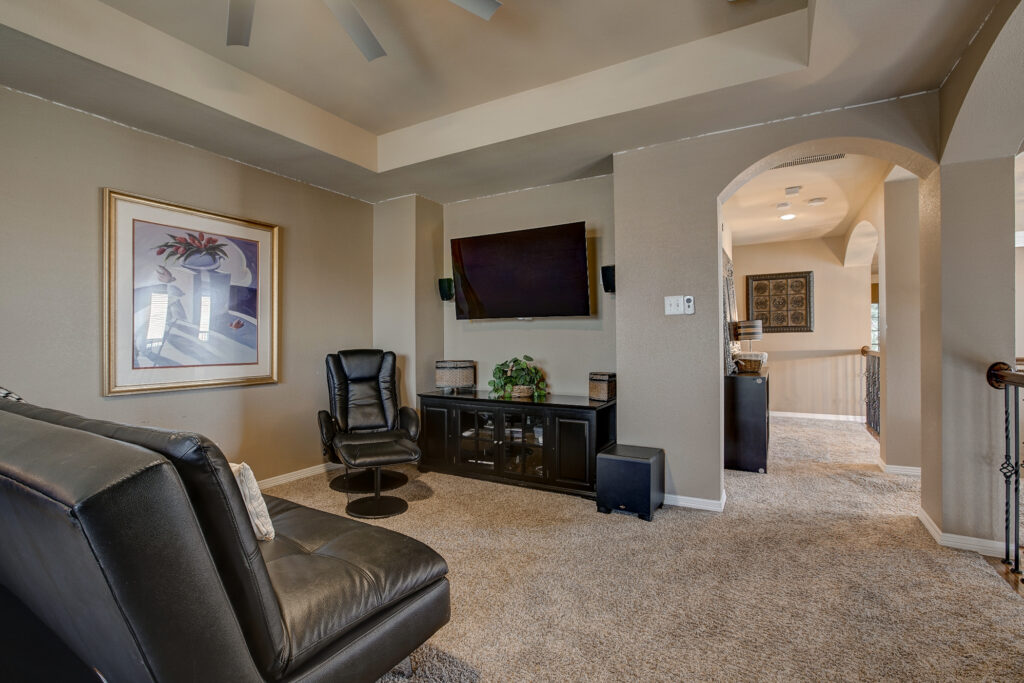 Upstairs game room with seating, mounted TV, and carpeted floors