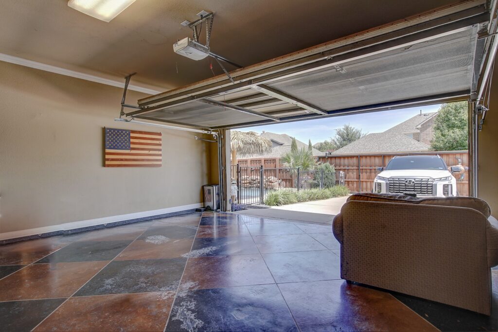 Garage with painted concrete floors, view of driveway and backyard gate