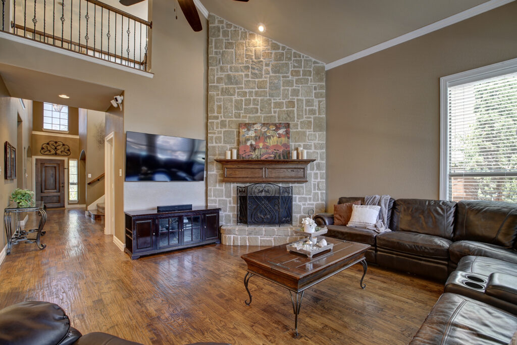 Living room with stone fireplace, sectional couch, and mounted TV