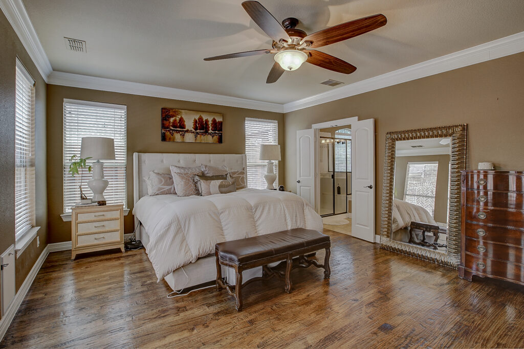 This primary suite offers rich hardwood floors, double door access to the bathroom, and ample room for a full bedroom set and entertainment center.