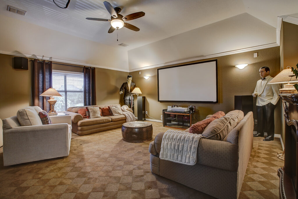 Upstairs media room with large sectional, projector screen, and dark curtains