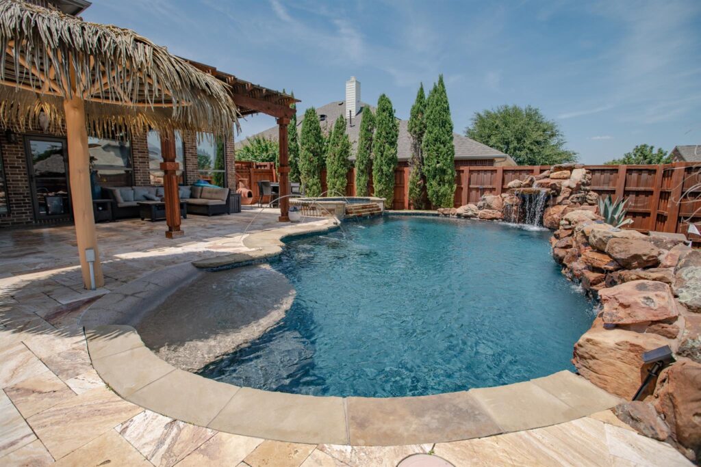 Backyard pool with waterfall, tanning ledge, and pergola seating area