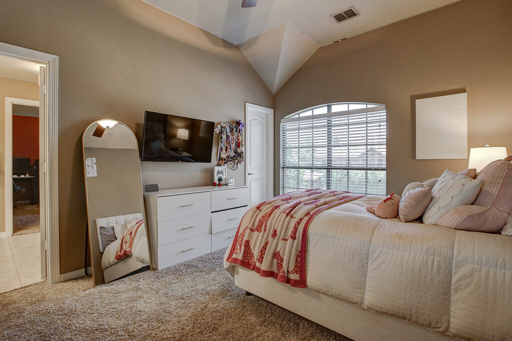 Cozy bedroom with dresser, TV, and large arched window