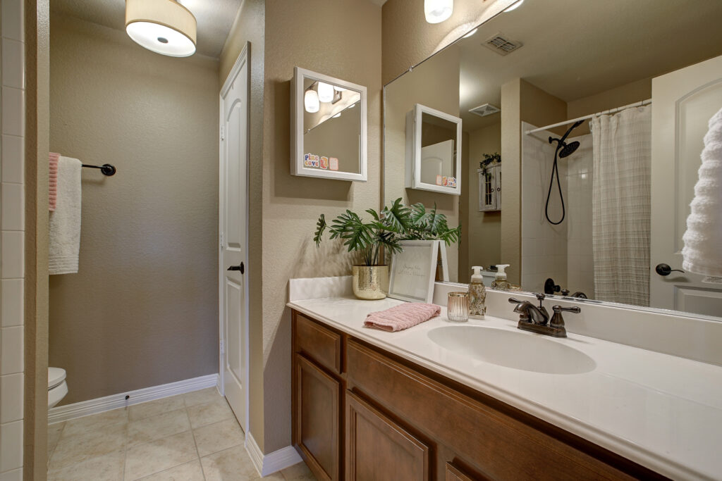 Full bathroom with single vanity, mirror, and shower tub combo