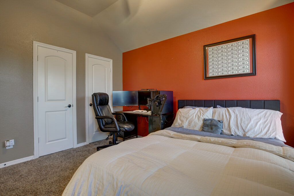 Teen bedroom with bed and gaming desk against red accent wall