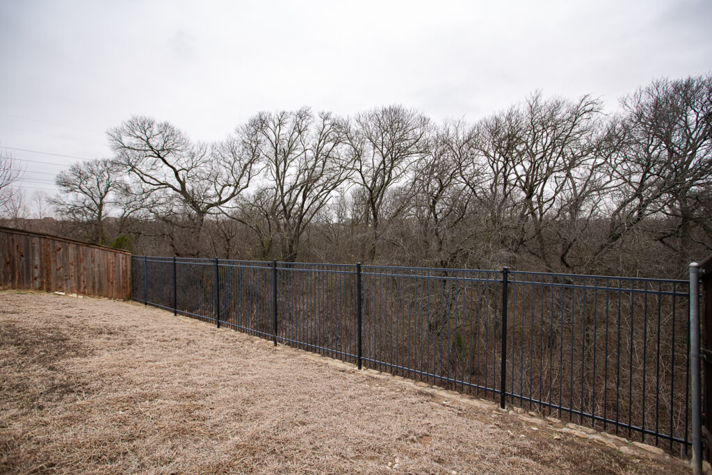 Iron fence with view of trees behind Wylie backyard