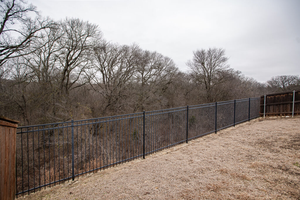 Iron fence lining backyard with wooded view in Wylie
