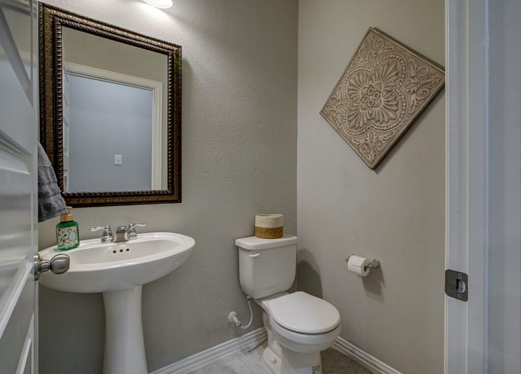 Compact powder bathroom with pedestal sink and framed mirror
