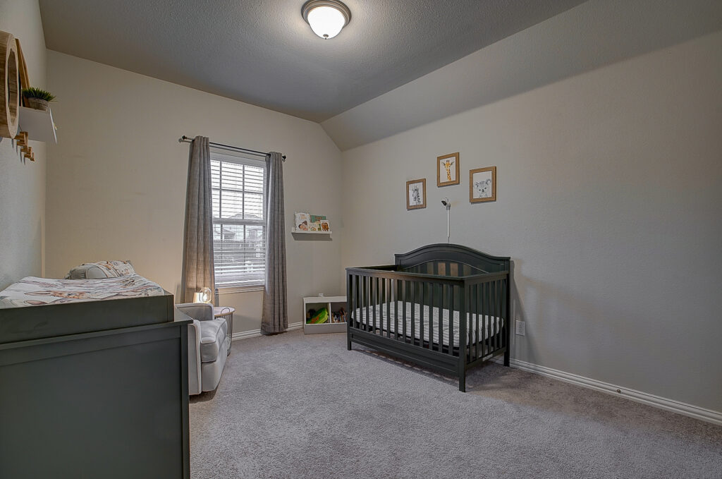 Nursery-style bedroom with crib, changing table, and framed animal prints