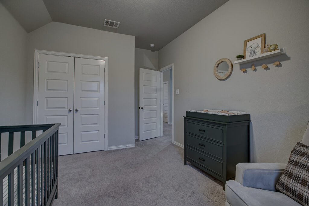 Secondary bedroom with neutral carpet, double-door closet, and nursery setup