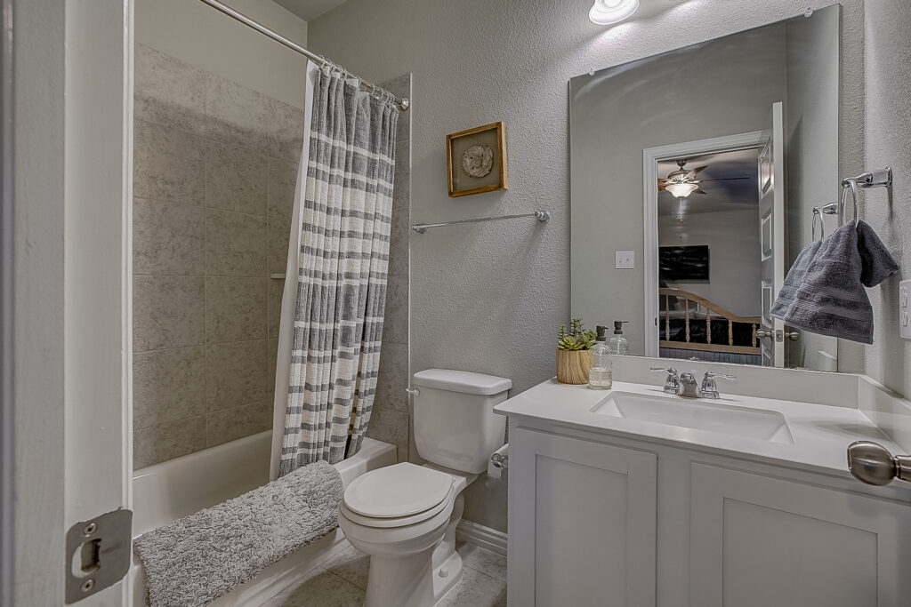 Full bathroom with tile tub surround, modern vanity, and large mirror