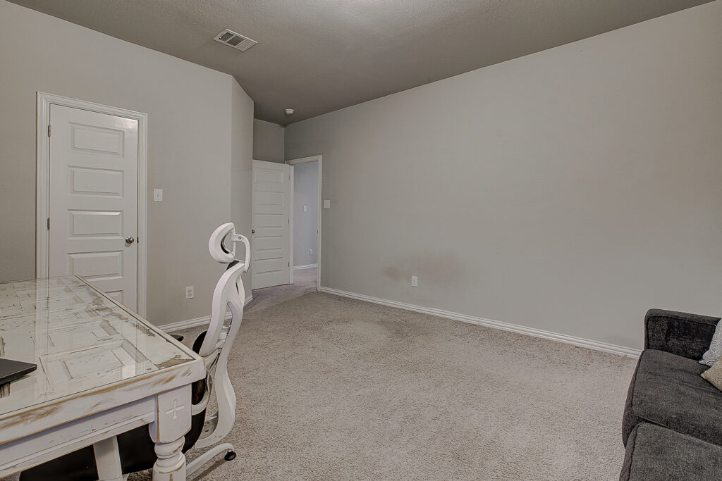 Oversized secondary bedroom with neutral carpet and attic access