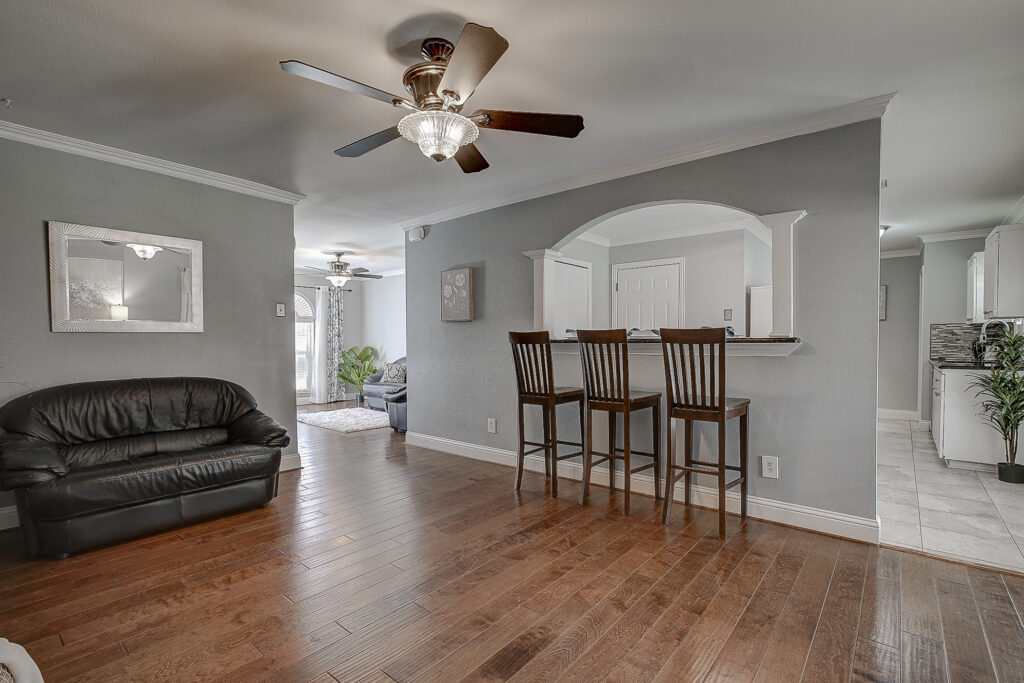 Main living area at 5302 Saddleback Rd Garland TX with breakfast bar, arched opening, and wood flooring