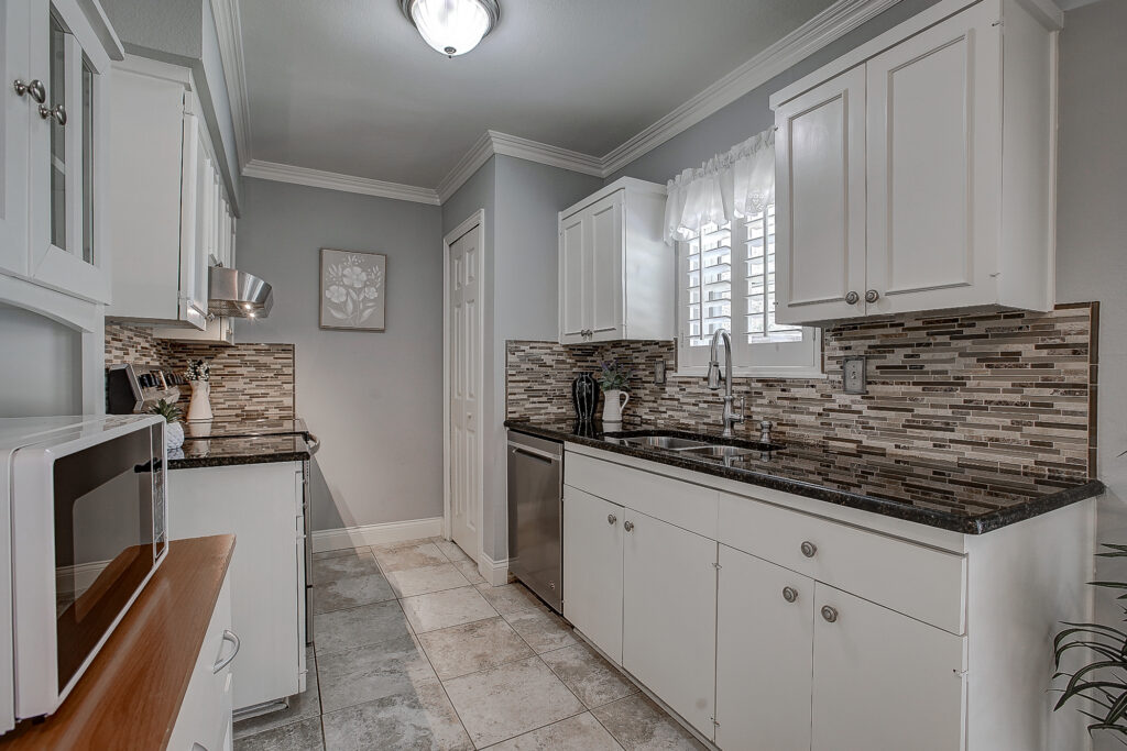 Kitchen at 5302 Saddleback Rd Garland TX with granite countertops, tile backsplash, white cabinets, and double sink