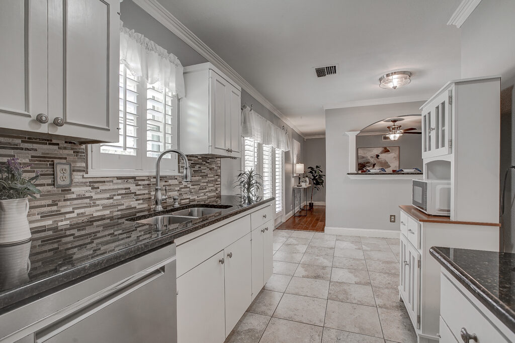 Kitchen at 5302 Saddleback Rd Garland TX with double sink, window with shutters, and granite countertops