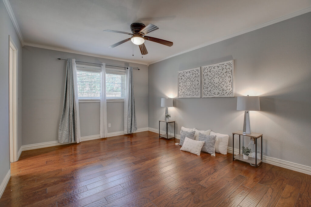 Primary bedroom at 5302 Saddleback Rd Garland TX with wood flooring, ceiling fan, and large window