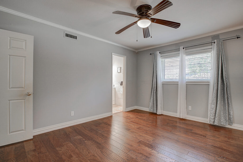 Primary bedroom at 5302 Saddleback Rd Garland TX with wood floors, ceiling fan, and access to ensuite bathroom