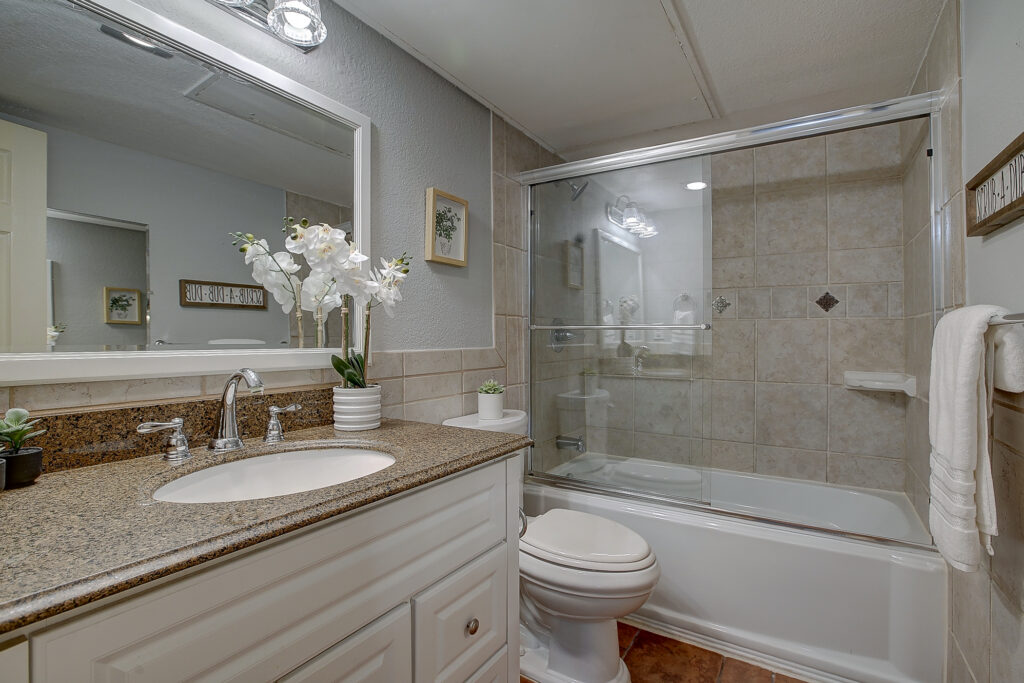 Secondary bathroom at 5302 Saddleback Rd Garland TX with vanity, tub shower combo, and tile surround