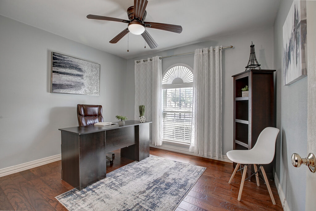 Secondary bedroom or office at 5302 Saddleback Rd Garland TX with wood flooring, ceiling fan, and window