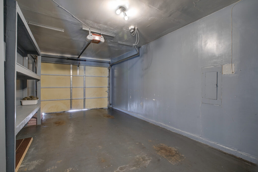 Garage at 5302 Saddleback Rd Garland TX with overhead door, storage shelves, and concrete flooring