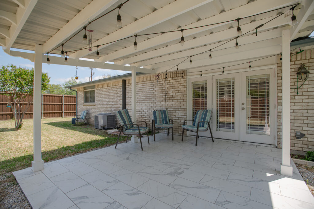 Covered back patio at 5302 Saddleback Rd Garland TX with tile flooring, string lights, and seating area