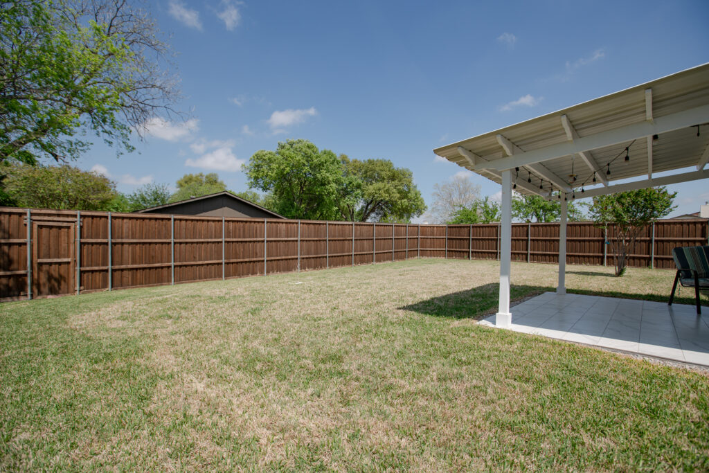 Backyard at 5302 Saddleback Rd Garland TX with large fenced yard and covered patio