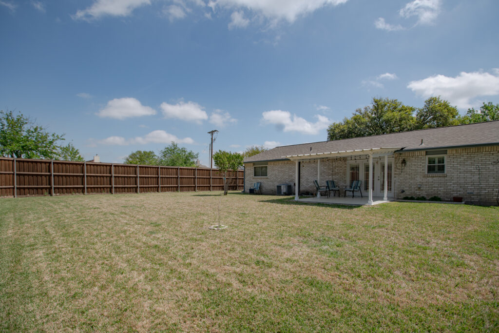 Backyard at 5302 Saddleback Rd Garland TX with covered patio, lawn, and fenced perimeter