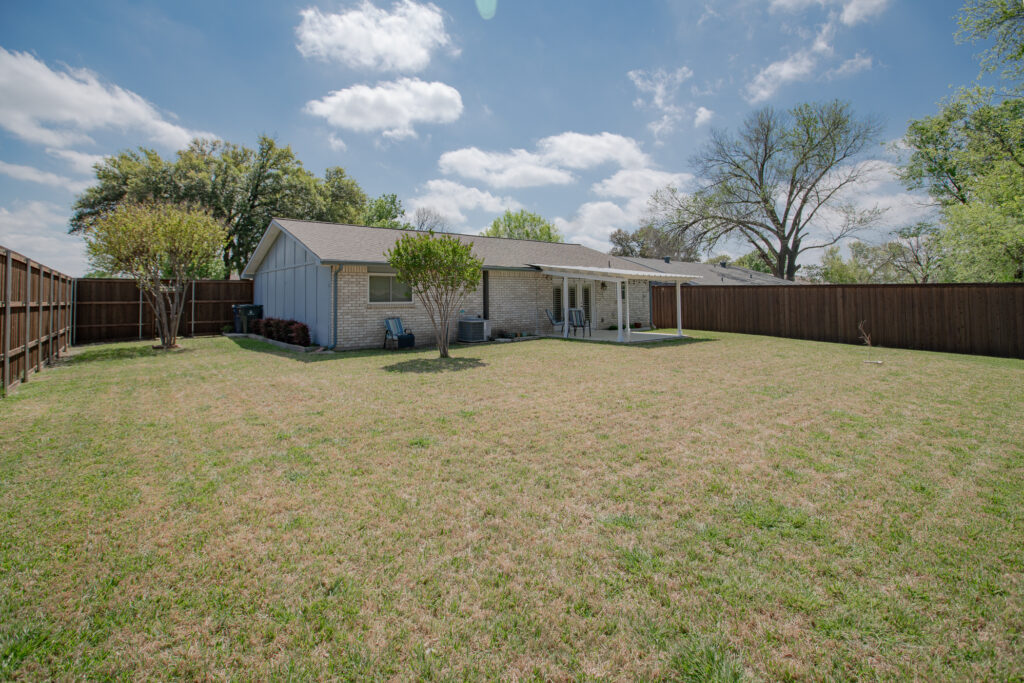 Rear exterior at 5302 Saddleback Rd Garland TX with covered patio, yard, and fencing