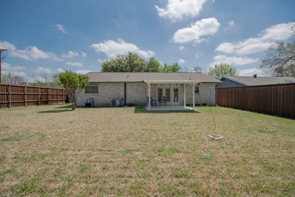 Large backyard at 5302 Saddleback Rd Garland TX with covered patio, fenced yard, and mature trees