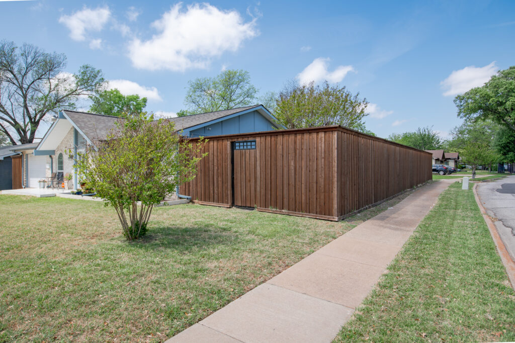 Side view of 5302 Saddleback Rd Garland TX showing wood privacy fence, gated access, and sidewalk