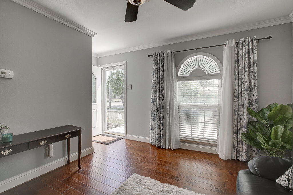 Living room at 5302 Saddleback Rd Garland TX with wood flooring, arched window, natural light, and front entry view