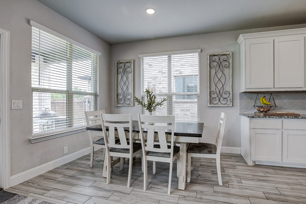 Dining nook with large windows, wood-look tile floors, and open kitchen layout in Lavon TX