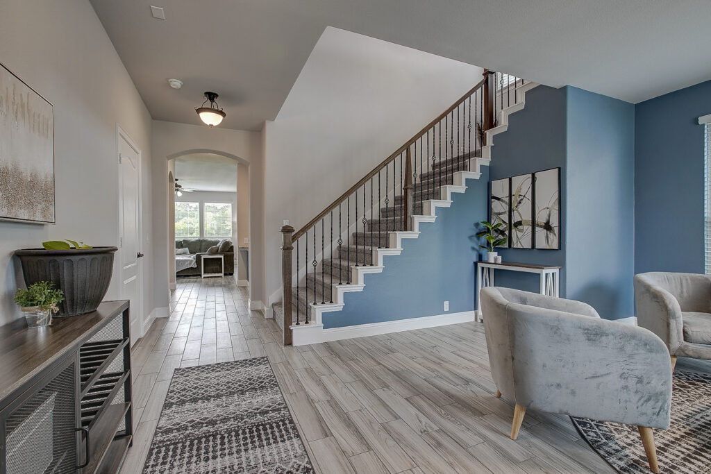 Open foyer with staircase, wood-look tile flooring, and formal sitting room in a Grand Heritage East home