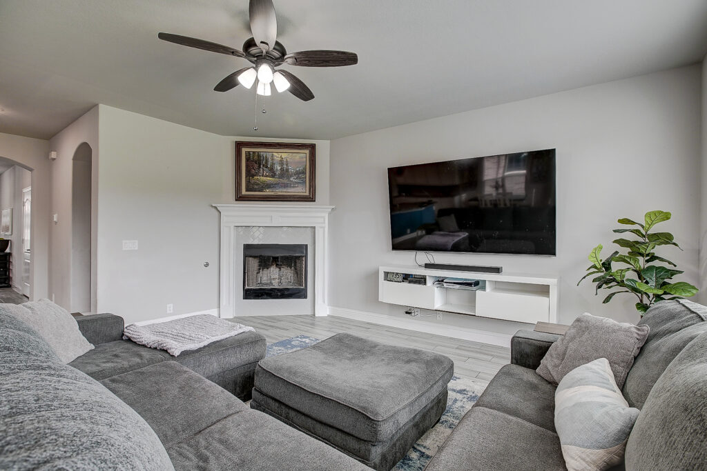 Bright family room with fireplace, wall-mounted television, neutral finishes, and open layout in Lavon TX