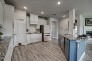 Kitchen with gas cooktop, granite counters, white cabinetry, and open breakfast area in Lavon TX