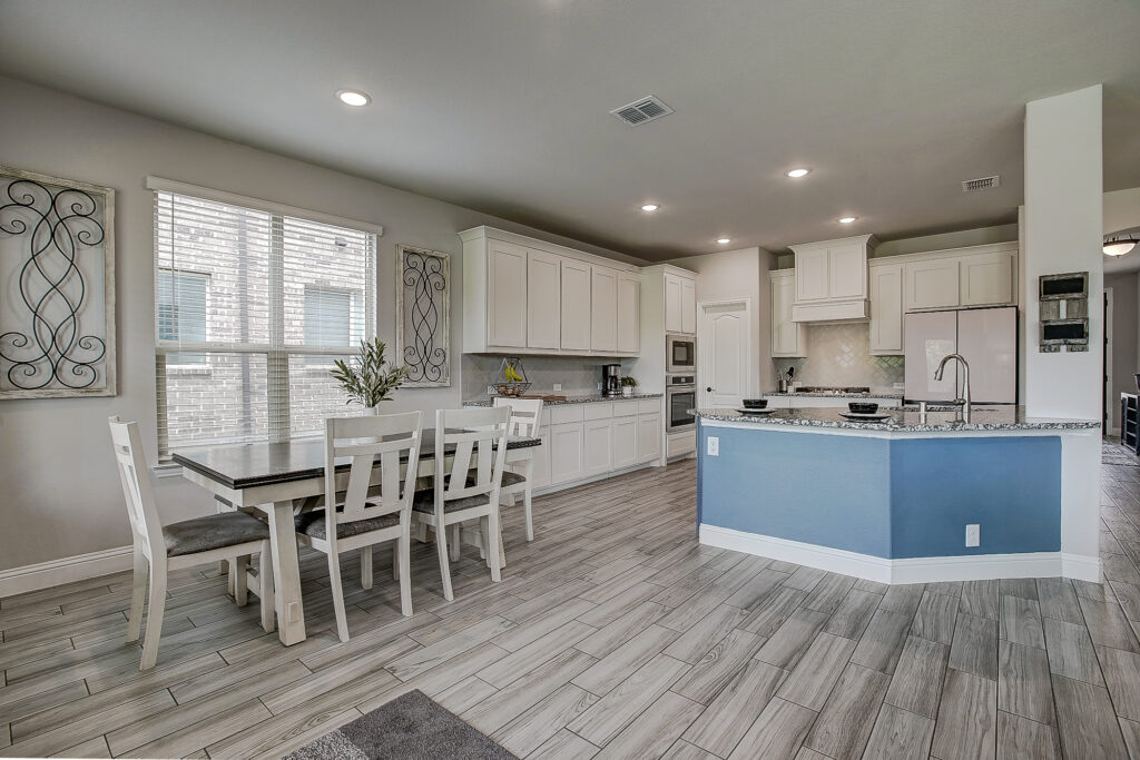 White kitchen with granite countertops, oversized island, recessed lighting, and stainless steel appliances